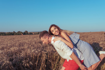 Young couple woman and man play in summer. Happy rejoice fun and laugh. Romance in a wheat field in fresh air. Strong love, and happy relationships. Free space for text.