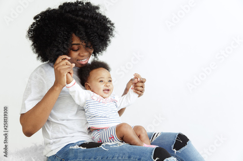 Closeup portrait of beautiful african woman holding on hands her little daughter on white background. Family, love, lifestyle, motherhood and tender moments concepts. Mother's day concept or