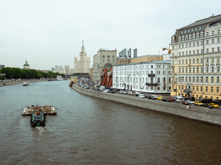 Obraz premium Stalin skyscraper on the background of the river with a boat. Moscow River view of the Stalinist skyscraper. cargo boat runs on the Moscow River