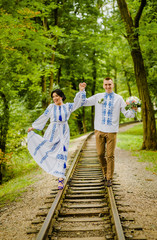 Fototapeta premium Happy couple in ethnic clothes going along the track holding hands