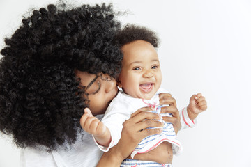 Closeup portrait of beautiful african woman holding on hands her little daughter on white background. Family, love, lifestyle, motherhood and tender moments concepts. Mother's day concept or