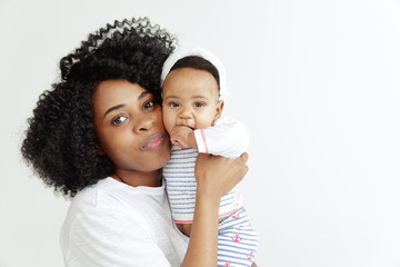 Closeup portrait of beautiful african woman holding on hands her little daughter on white background. Family, love, lifestyle, motherhood and tender moments concepts. Mother's day concept or