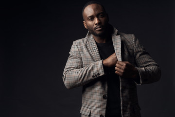 Serious man in brown plaid suit jacket. One hand in inner pocket. Studio shot