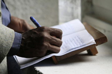 Pèlerin africain écrivant un message sur un livret de recueil. / Pilgrim African writing a...