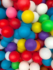 Fototapeta na wymiar Top view colorful plastic balls in a pool. Plastic colorful balls for playing. Colorful plastic gum balls background in kid playroom or playground for children's holiday party concept