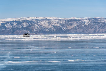 Baikal lake in winter day. Cracks on surface of the natural ice in frozen water behind the mountains at Baikal lake, Russia