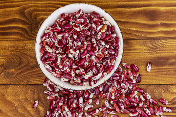 Raw kidney beans in white old enameled bowl on wooden table