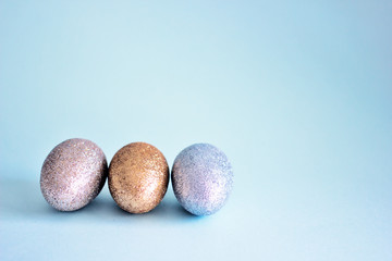 Three Easter eggs in silver shades on a blue background, copy space. Easter Background