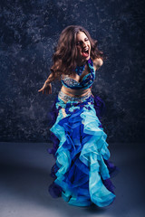 Young attractive girl in a blue suit dancing belly dance.