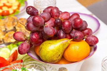 Naklejka na ściany i meble Grapes, pear and orange on the plate