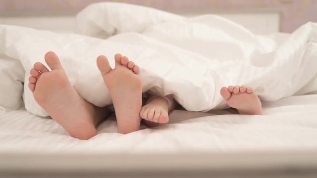 Little kid's feet stick out from under the blanket