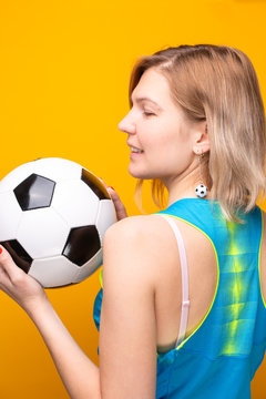 Photo from back of blonde with soccer ball on yellow background