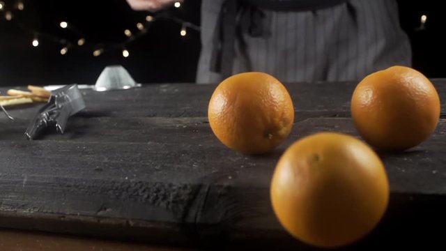 Cook throws oranges on a wooden table, cooking in slow motion