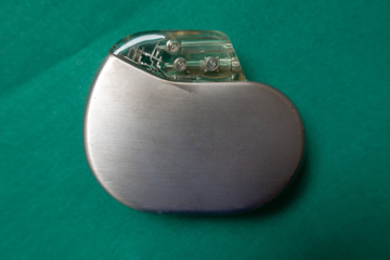 an explanted pacemaker on a green surgical drape