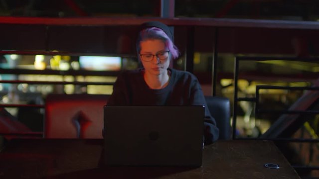Zoom in of female hipster sitting at laptop in caf&eacute; and programming