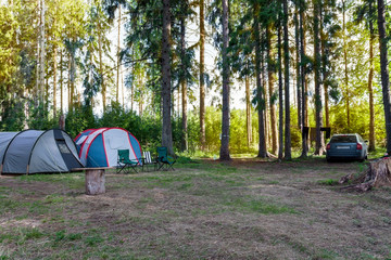 Parking tourists in the forest. Two tents and a car