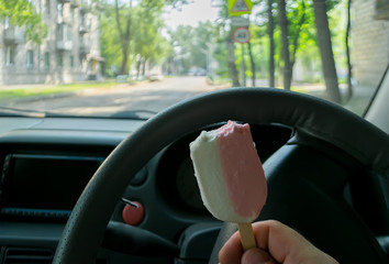 the driver holds the ice cream while driving a car