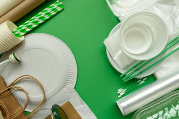 Plastic, paper and glass packages on green background. Copy space. Top view. Eco and save earth concept.