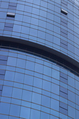 Fototapeta na wymiar Vertical clear shoot of blue colored glazing facade mass office building