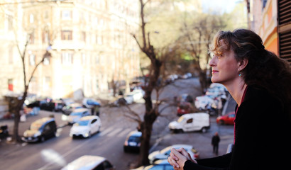 beautiful mature woman standing on the balcony looking to the street