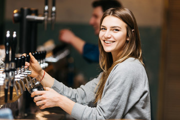 Smiling blonde at coffee machine in cafe.