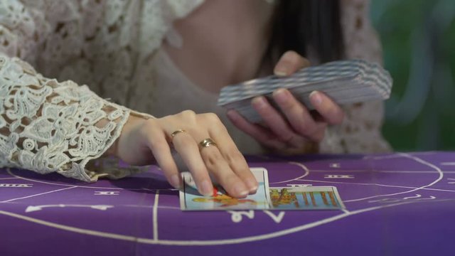 Tarot reader dealing cards & reading future and fortune. Day. Window & trees background. Modern. White dress. 4k.