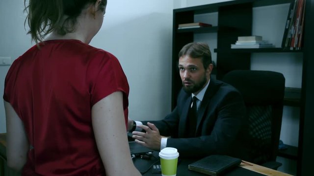 bearded businessman sitting in the office at the laptop, girl in red is trying to seduce the boss, slow motion.