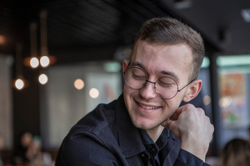 Side view of a smliling businessman talking on a phone while sitting in cafe, drink smoothy, eat pie