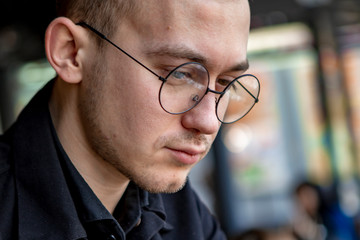 Young stylish man enjoys a cake and a drink while sitting in a cafe with large windows