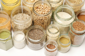 Top view of jars with grains, seeds, legumes, flours and various food ingredients. Healthy food concept.