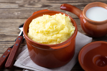 Mashed potatoes in a clay pot, vintage wood background, rustic style.