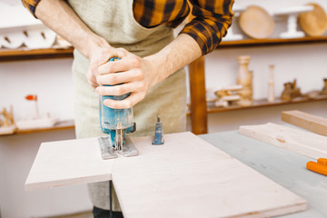 man carpenter working with a jigsaw on wood in the workshop