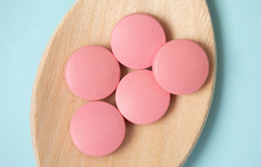 medicine tablets on a wooden spoon isolate on blue background.