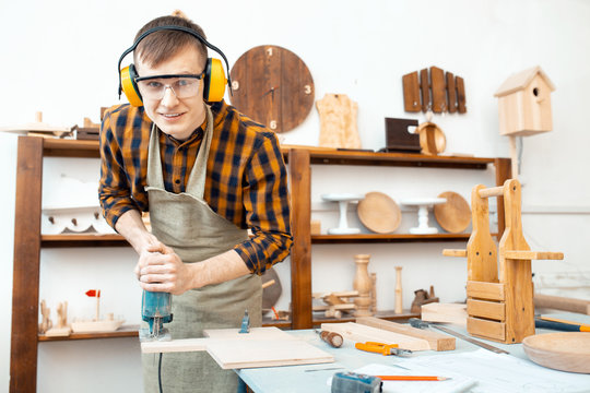 man carpenter working with a jigsaw on wood in the workshop