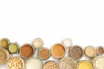 Top view of jars with grains, seeds, legumes, flours and various food ingredients. Healthy food concept.