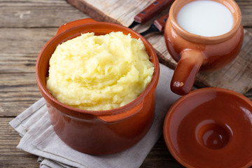 Mashed potatoes in a clay pot, vintage wood background, rustic style.
