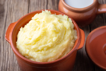 Mashed potatoes in a clay pot, vintage wood background, rustic style.