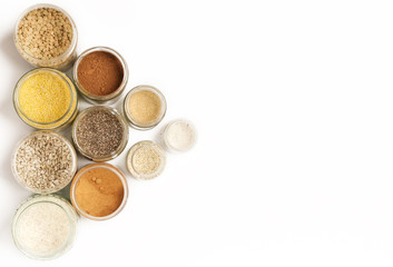 Top view of jars with grains, seeds, legumes, flours and various food ingredients. Healthy food concept.