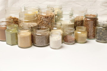 Many jars with grains, seeds, legumes, flours and various food ingredients. Healthy food concept.