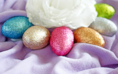 Colorful Easter eggs with glitter on turquoise fabric, copy space. Background about Easter. Colorful painted eggs for Easter