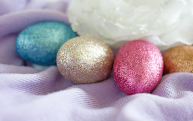 Colorful Easter eggs with glitter on turquoise fabric, copy space. Background about Easter. Colorful painted eggs for Easter
