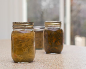 Homemade pickled relish bottles on kitchen counter top.