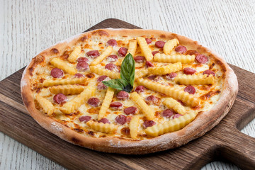 Pizza for children, with sausages and french fries on a wooden board
