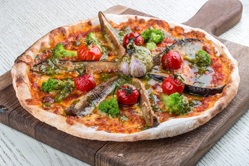 Vegetarian pizza with eggplant, broccoli and garlic on a wooden board