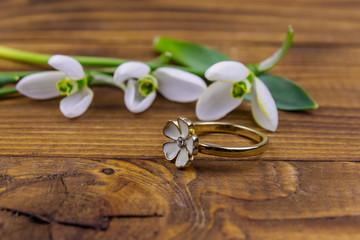 Golden ring and snowdrops on wooden background