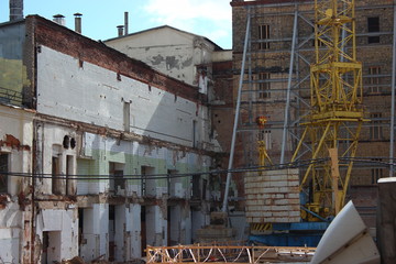 the destruction of the old building, reconstruction, structural changes. construction, high-rise crane works on the site. the building is made of brick, tiles on the walls. 