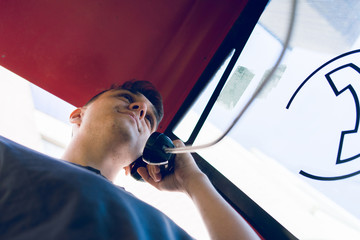 Low angle view of young man making a call from public phone box