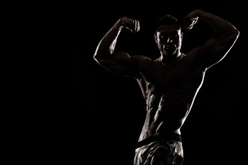 Bodybuilding competitions on the scene. Man sportsmen physique and athlete. Black background.