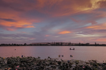 Naklejka premium Lake view evening of many clouds moving in the sky with colorful red sun light in the sky background, sunset at Krajub reservoir, Banpong, Ratchaburi, Thailand.