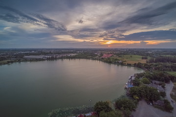 Aerial view evening of dark clouds moving above the lake with colorful of yellow sun light in the sky, sunset at Krajub reservoir, Banpong, Ratchaburi, Thailand.